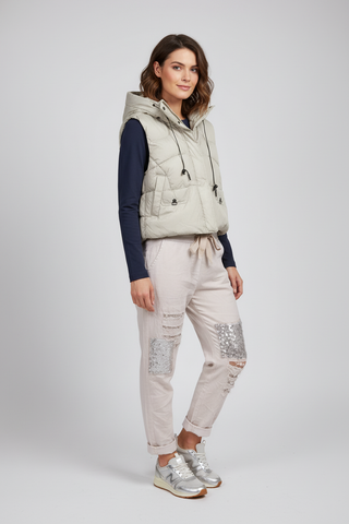 Woman wearing a light-colored vest and pants on a white background